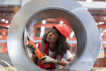 African female worker working with remote control's operating crane or lifting beam in factory