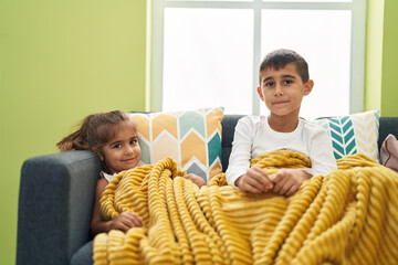 Brother and sister smiling confident sitting on sofa at home
