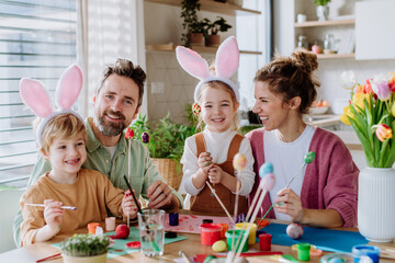 Happy family with little kids decorating easter eggs.