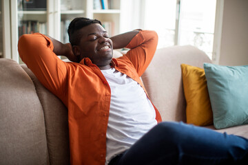 Relaxed plus size black guy chilling on couch at home