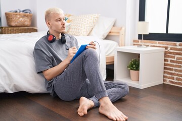 Obraz premium Young caucasian man drawing on touchpad sitting on floor at bedroom