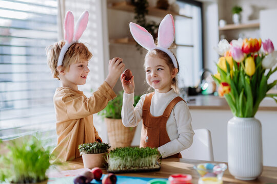 Little kids with bunny ears celebrating easter, playing easter game with egg.