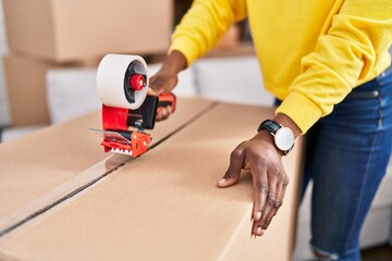 African american woman packing cardboard box at new home