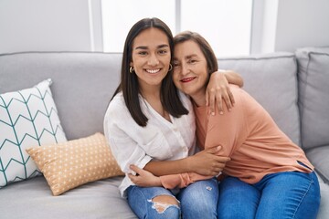Obraz premium Two women mother and daughter sitting on sofa together at home