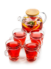 Red fruit tea with oranges, kiwi, strawberries in a glass teapot and cups. On a white background , isolate