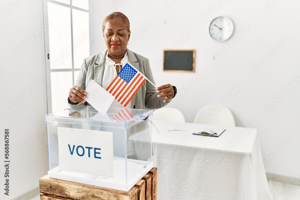 Canvas Prints Senior african american woman holding united states flag voting at electoral college