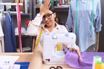Young arab woman dressmaker designer working at atelier surprised with hand on head for mistake,...