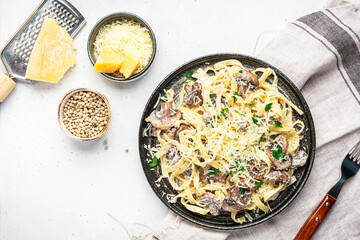 Tagliatelle pasta with mushrooms served on plate with parsley and spices on grey stone kitchen table background, top view. Healthy cooking and eating. Italian food concept