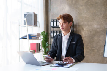 Young asian businessman sitting working with laptop computer in office.
