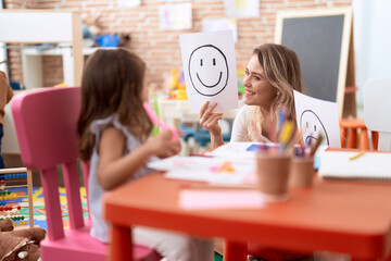 Teacher and toddler sitting on table having emotion therapy at kindergarten
