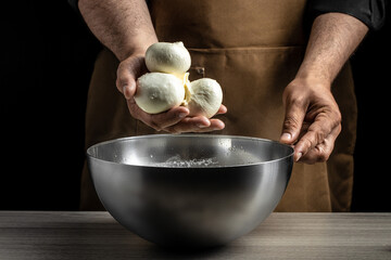 A man working in a small family creamery is processing the final steps of making a cheese. Italian hard cheese silano or caciocavallo, mozzarella