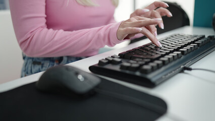 Young blonde woman student using computer studying at library university