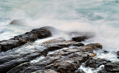 Waves crashing of flat rocks on shoreline