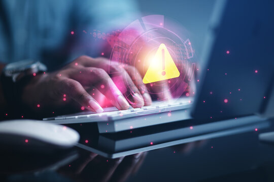 Businessman, programmer, developer using laptop computer with triangle warning sign for error notification. Failure data protection concept
