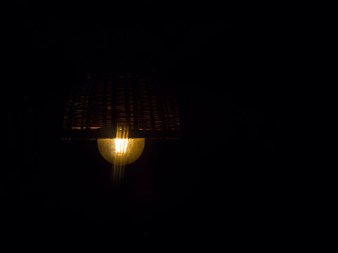 A light bulb in the night,  Underexposed photo of a beautiful wood lamp by Indian handmade design for decoration.