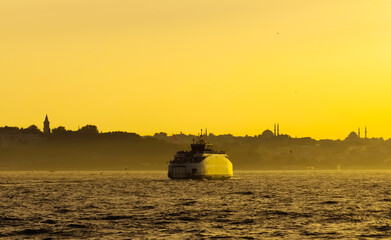 A ferry is seen on Bosphorus in Istanbul, Turkey. Minarets of mosques seen in the background.
