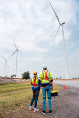 Group of engineers discussed about maintenance schedule of wind turbines. Renewable energy power plant with wind generator at wind farm by alternative energy concept.