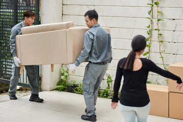 House owner showing movers where to put new sofa she bought