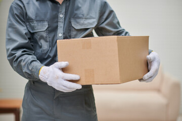 Cropped image of mover in grey uniform holding cardboard box