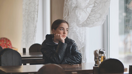 A lonely young girl sits in a cafe.