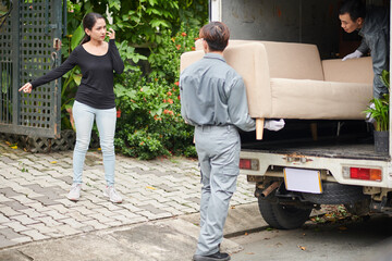 Obraz na płótnie Canvas House owner meeting movers at gates and showing where to carry couch she ordered