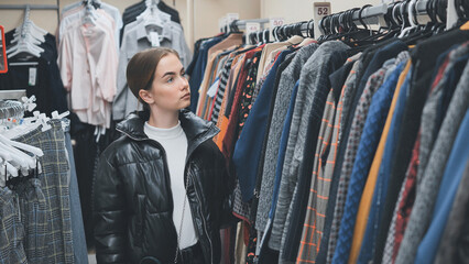 A young girl choosing and looking at clothes in the store.