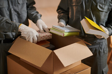 Closeup image of movers putting books in cardboard boxes
