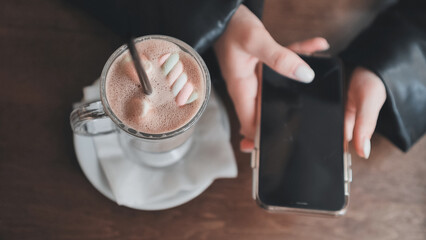 The girl is about to drink cuppuccino and lays down her smartphone.