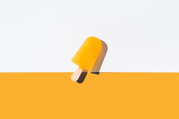 Paleta de hielo naranja. Palo de helado de pie sobre fondo naranja y blanco. Concepto de verano....