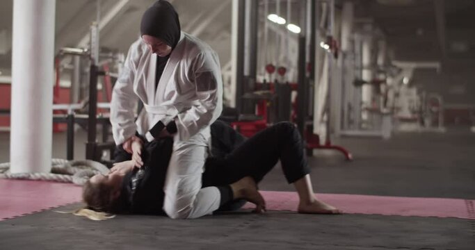 Muslim woman wrestling with opponent on floor