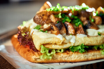 Breakfast sandwich with Omelette and mushrooms and white sauce. Concrete background. Hard light. Vegetarian food. Close up