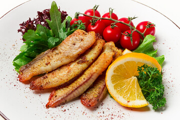 Fried Tilapia fish fillet, in spices, with cherry and salad, on a white plate, homemade, no people,