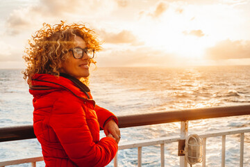 Portrait of a cheerful young adult woman enjoying sunset outside traveling the ocean on a ferry...