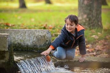 young caucasian boy playing in urban park in autumn