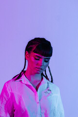 Portrait of a beautiful and attractive girl with parted mouth and braid hairstyle in neon purple and pink. Neon background.