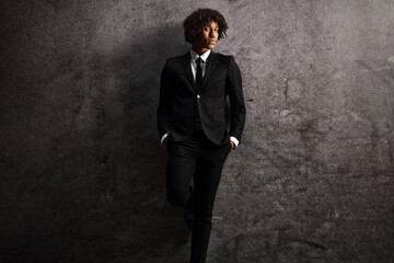 Young african american male model in a suit and tie leaning on a rusty wall