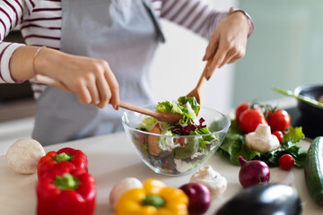 Obraz na płótnie Canvas Female chef making fresh vegetable salad, preparing meal at home