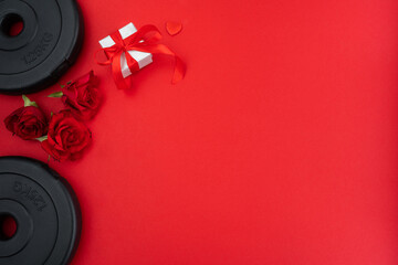 Gym workout dumbbells barbell weight plates, red roses flowers and engagement ring box as a love...