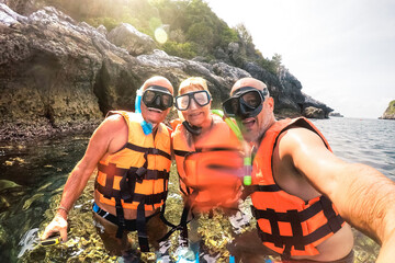 Senior mother and father with son taking selfie at snorkel excursion in Thailand - Adventure travel...
