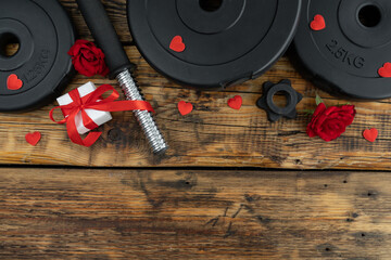 Gym workout dumbbells barbell weight plates, red roses flowers and engagement ring box as a love...