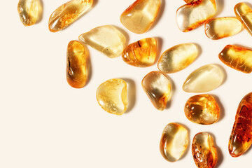 Amber stones at sunlight on beige background, minimal style frame with transparent stones in line, color gradient. Natural gemstone mineral, healing crystal. Top view Amber Nature gems