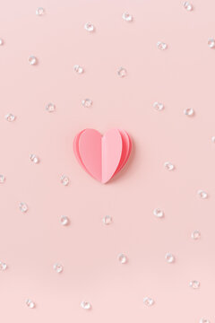 Heart with sequins, rhinestones on pastel pink background, St. Valentine Day, love or wedding day concept. Cut pink paper heart as symbol romantic relationships, minimal aesthetic vertical