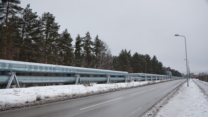 pipeline and road against the backdrop of forest and gray sky