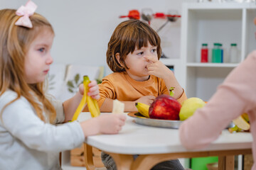 Children eating a fruit snack in a kindergarten 