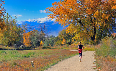 Female jogger on Boulder, Colorado's Teller Farm Trail in autumn, with the Continental Divide in the background