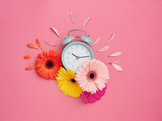 Spring time concept. Creative flat design with turquoise alarm clock on pink background with...