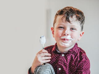 adorable elementary school child eats yogurt for breakfast