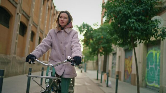 young hipster enjoying cycling on her city bike in an old green European street 