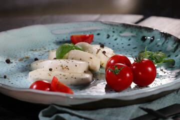 Traditional italian plate with white mozzarella, cherry tomato, basil and olive oil.