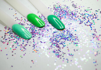 Samples of nail polish in green on a light background with sequins.